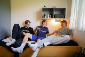 Tre drenge sidder i en seng og griner